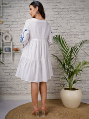 White maternity dress with blue floral embroidery and tiered silhouette