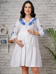 White maternity dress with blue floral embroidery and tiered silhouette